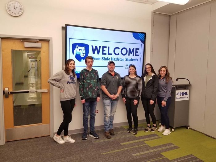 Group of students standing in front of a digital screen that says "Welcome, Penn State Hazleton students"