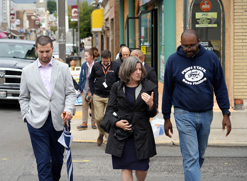 Three people smiling and walking together across a downtown street.