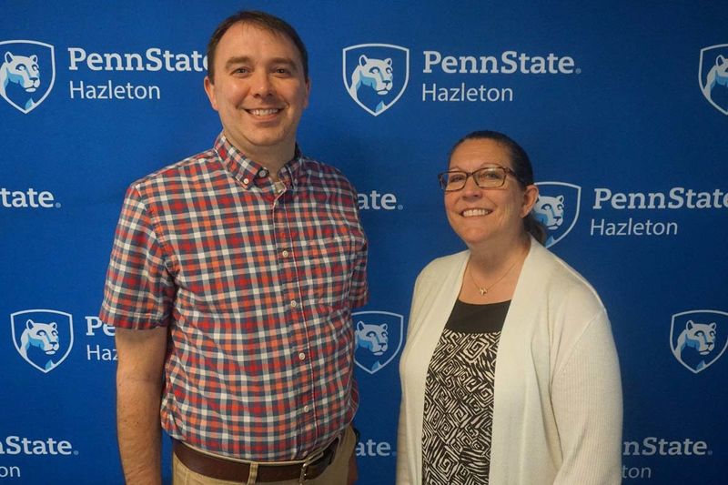 Man and woman smiling in front of Penn State Hazleton backdrop.