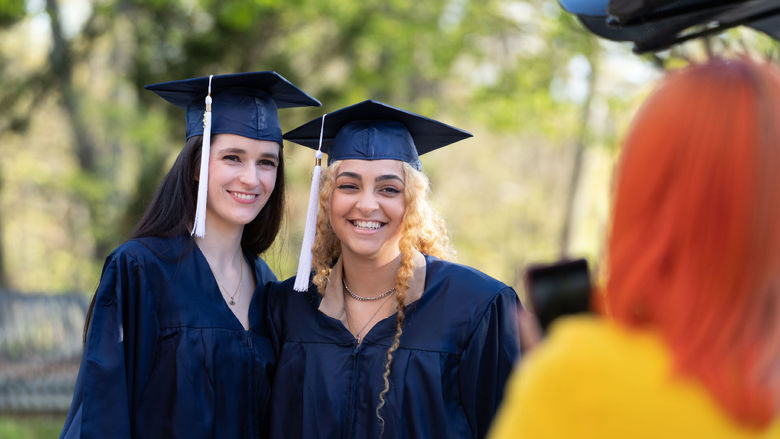 Female students in caps and graduation gowns smiling outdoors.