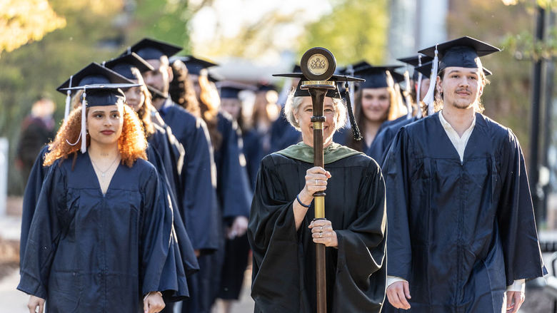 Penn State Hazleton graduates walking side by side down a sidewalk.