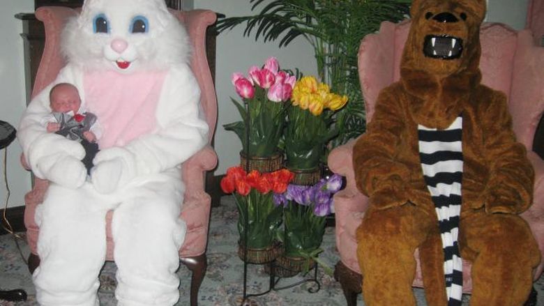 Easter bunny holding a baby and seated in a chair next to Nittany Lion
