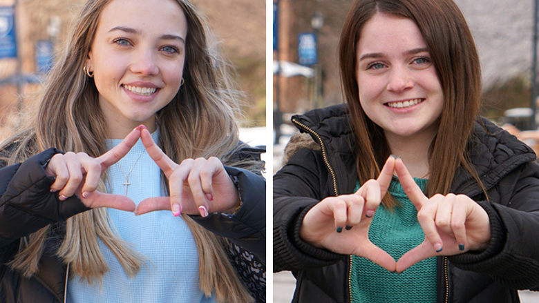 Two female students making diamond signs with their hands.