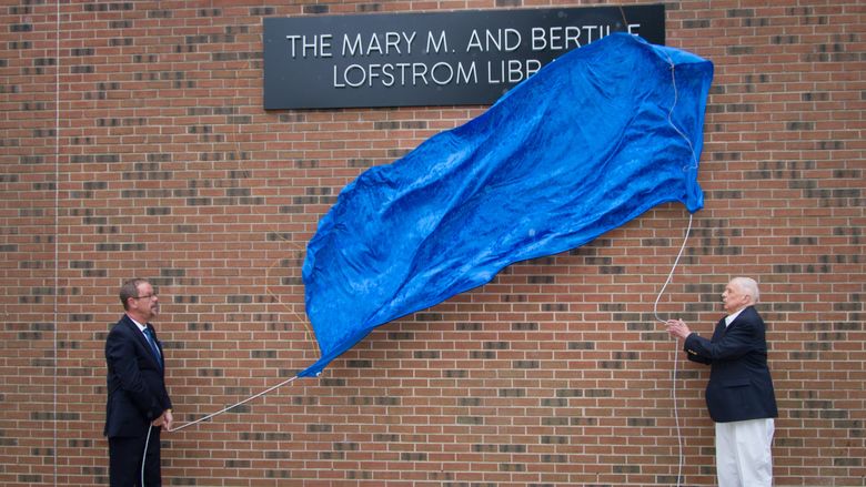Penn State Hazleton Chancellor Gary Lawler and donor Bertil Lofstrom drop the banner revealing the new name of the campus library.