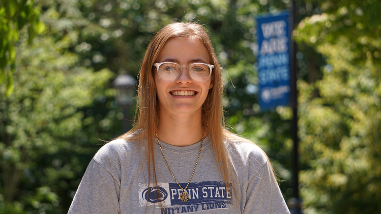 Female student in gray Penn State shirt standing outdoors.