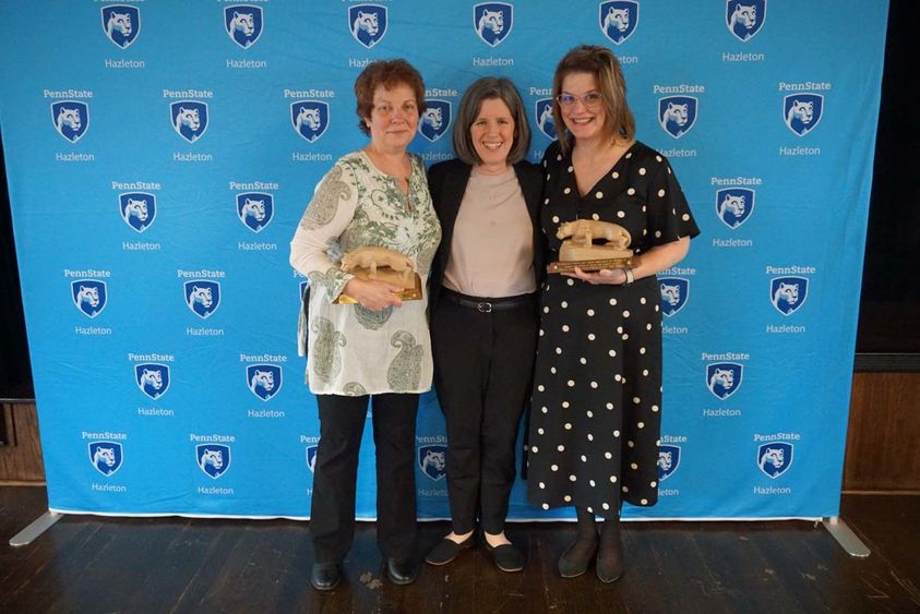 Three women standing in front of light blue Penn State Hazleton backdrop.
