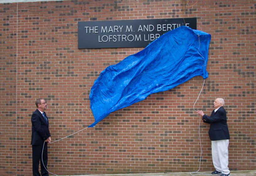 Penn State Hazleton Chancellor Gary Lawler and donor Bertil Lofstrom drop the banner revealing the new name of the campus library.