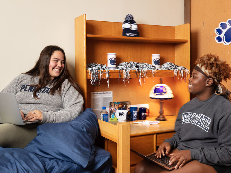 Students laughing and talking at a desk in residence hall.
