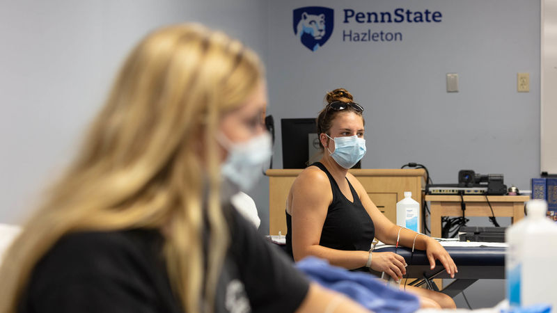 PTA students in masks examining physical therapy equipment.