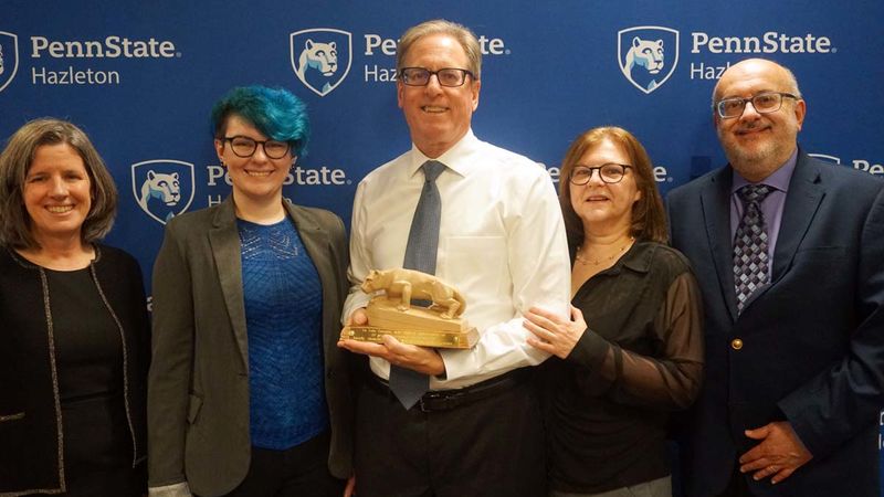 Group of people including one holding miniature Nittany Lion statue.