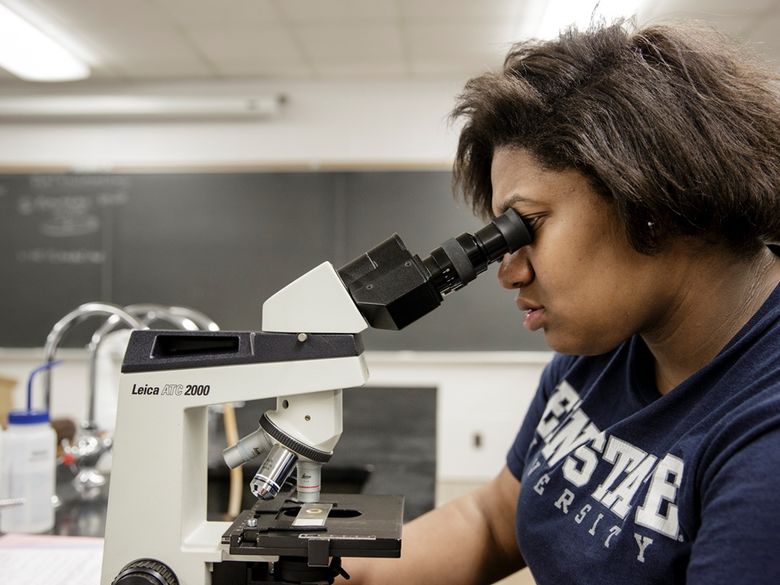 Female student looking through microscope.