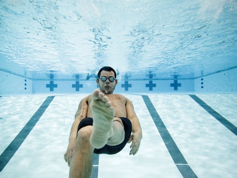 Male student swimming underwater in pool.