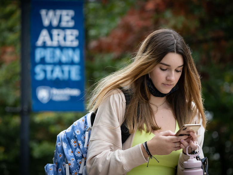 Female student looking at a cell phone while walking outdoors.