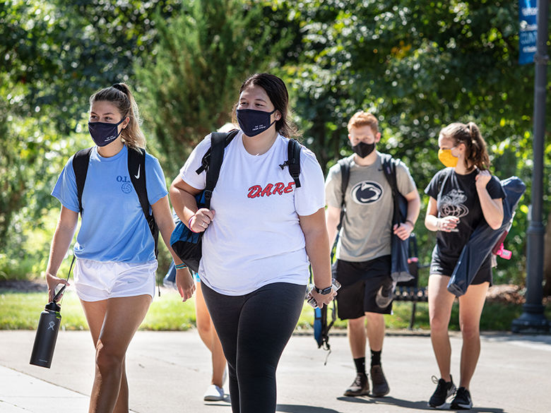 Group of students in masks walking along campus mall.