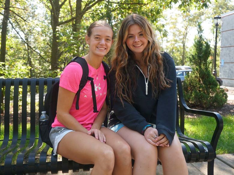 Two female students sitting on a bench outdoors.