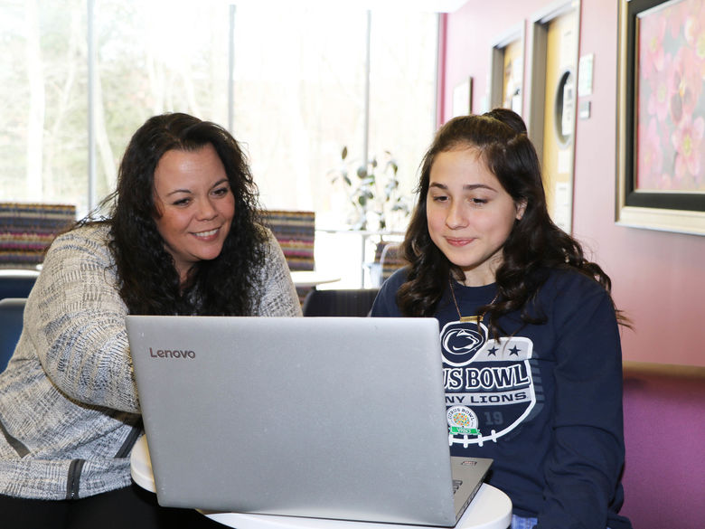 Student and staff member looking at a laptop screen together.