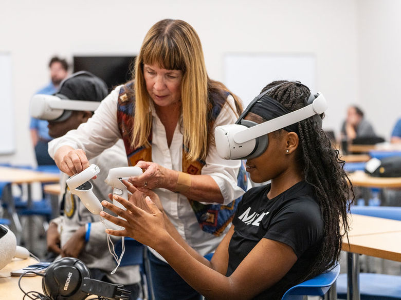 Instructor working with a female student using a virtual reality headset in a classroom.
