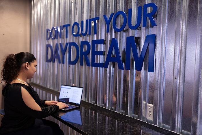 Student using laptop inside Hazleton LaunchBox next to wall that says "Don't Quit Your Daydream"