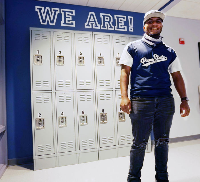 Student standing in front of lockers with "We Are" above.