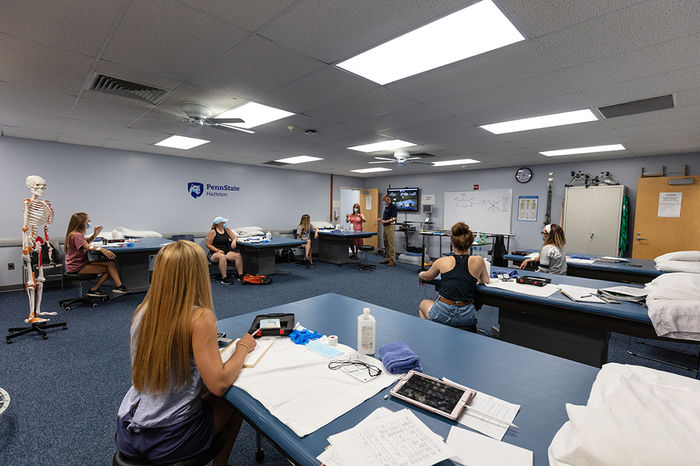 Physical therapy assistant students sitting at desks inside classroom with instructor teaching from front.
