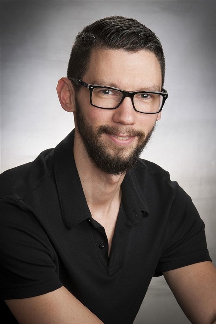 Man in glasses and black polo shirt posing for a photo
