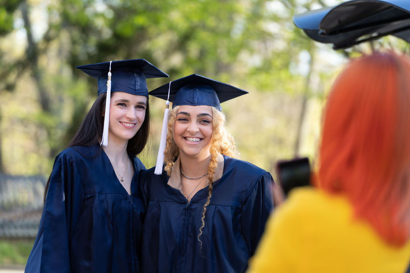 Female students in caps and graduation gowns smiling outdoors.
