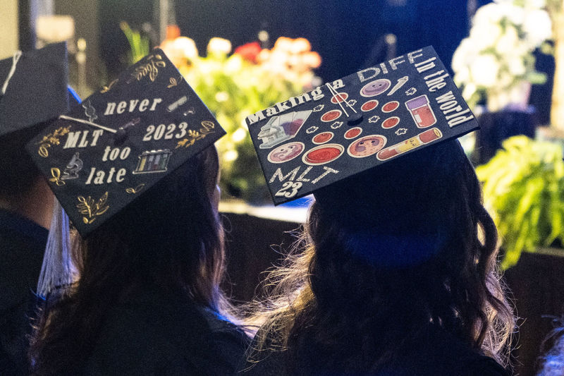 Two graduation caps decorated with stickers and text.