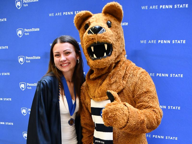 Female student standing next to the Nittany Lion mascot.