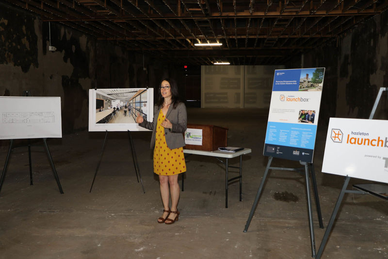 Woman with hands out standing in front of renderings on easels