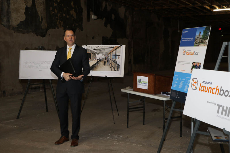 Man standing in a building undergoing renovation and talking to a group of people. 