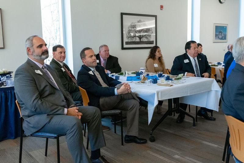 Group sitting at a table listening to a speaker talk.