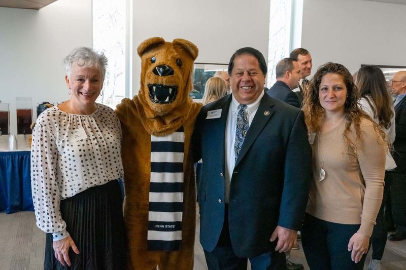 Group of three people smiling for photo next to Nittany Lion mascot.