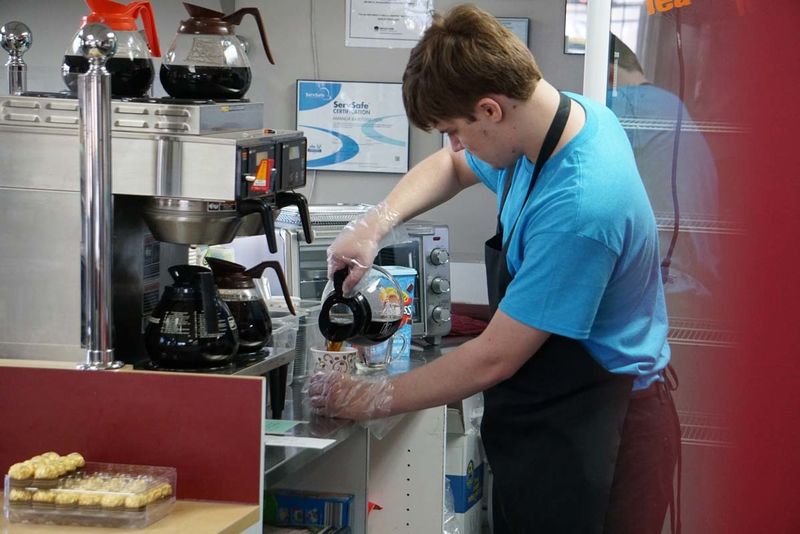 An employee pours a cup of coffee into a mug.