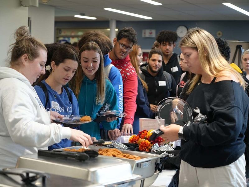 Students gathered around a buffet table putting food on plates.