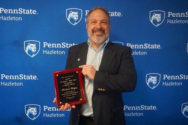 Man smiling and holding a plaque.