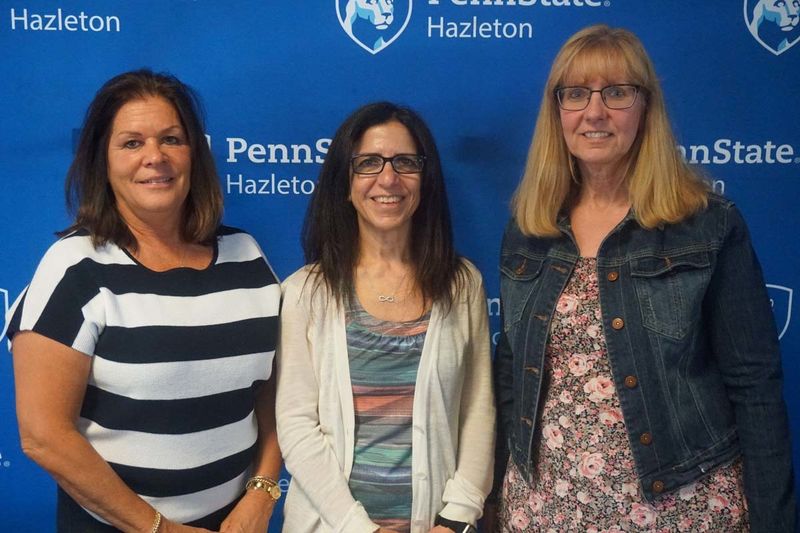 Group of three women smiling in front of blue Penn State Hazleton backdrop.