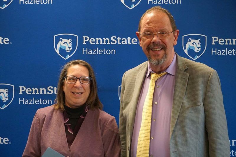 Woman and man standing side by side smiling.