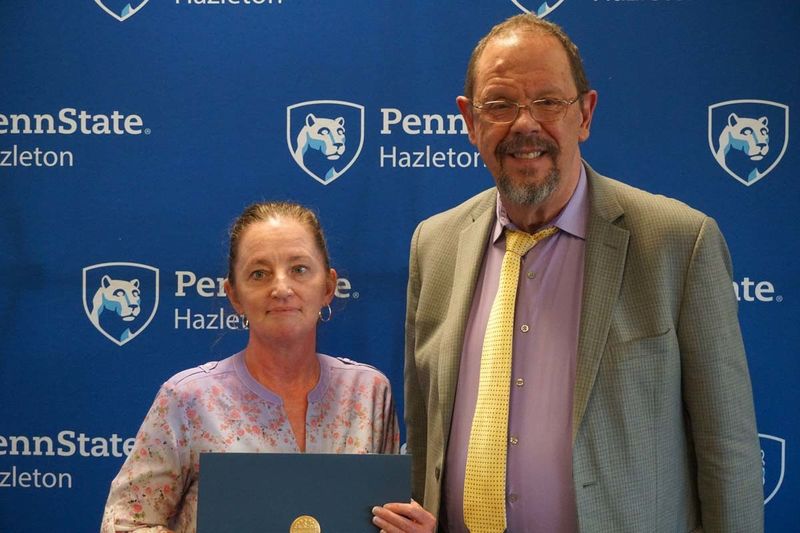 Woman holding certificate and standing next to man in suit.