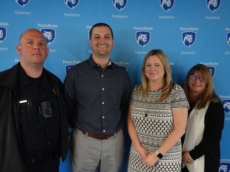 Four people standing in front of a light blue Penn State Hazleton backdrop