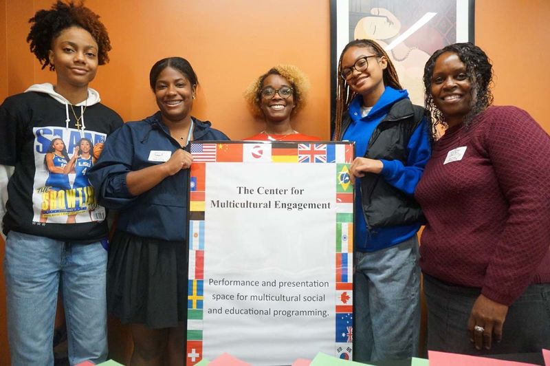 Group of women standing behind a poster promoting the Center for Multicultural Engagement.