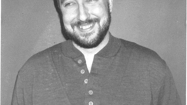 Black and white photo of man with beard and button-up shirt.