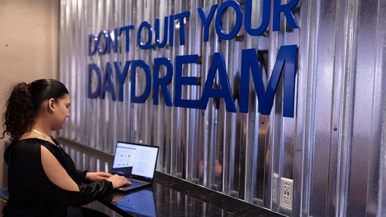 Student using laptop inside Hazleton LaunchBox next to wall that says "Don't Quit Your Daydream"
