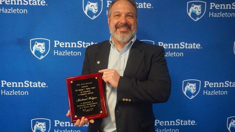Man smiling and holding a plaque.