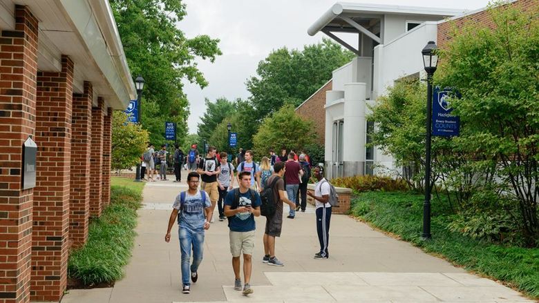 Students walking on a sidewalk at a college campus.