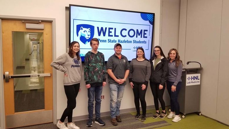 Group of students standing in front of a digital screen that says "Welcome, Penn State Hazleton students"