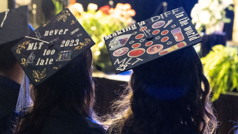 Two graduation caps decorated with stickers and text.