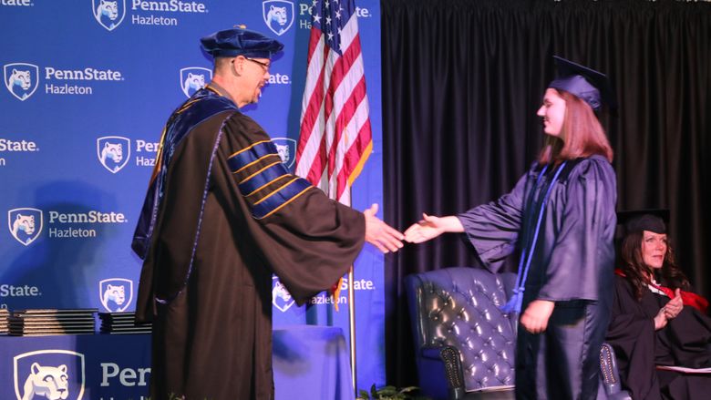 Graduate shakes hands with chancellor during commencement ceremony. 