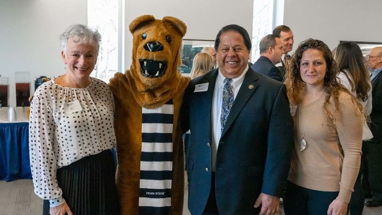Group of three people smiling for photo next to Nittany Lion mascot.