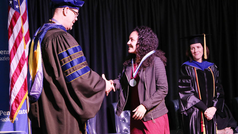 Student receives medal from chancellor at Academic Achievement Awards ceremony. 