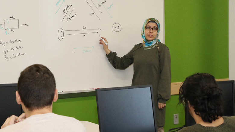 Assistant teaching professor of engineering Mesude Bayrakci-Boz in front of a white board with students during class.